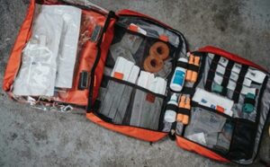 Rozłożona pomarańczowa apteczka górska z widoczną zawartością