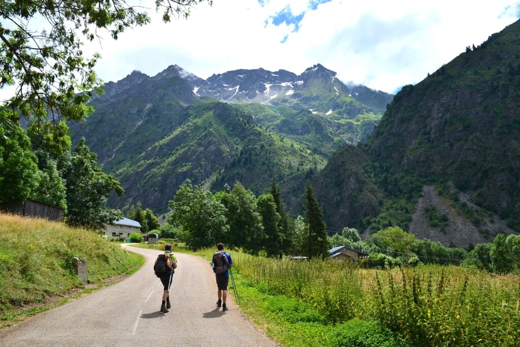 Dwaj wędrowcy podczas letniej wędrówki w stronę Masywu Ecrins. Przed nimi wyrastają majestatyczne Alpy.